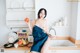 A woman sitting on a kitchen counter holding an apple.