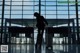 A woman walking through an airport with a suitcase.