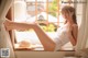 A woman in a white lingerie sitting on a window sill.