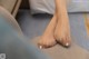 A woman's bare feet sitting on a couch.