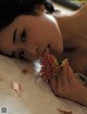 A woman laying on a bed with a flower in her mouth.