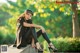 A woman sitting on a stone ledge in a park.