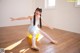 A young ballerina sitting on a yellow ball in a dance studio.