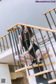 A woman in a black dress is sitting on the stairs.