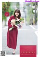 A woman in a red dress holding a bouquet of flowers.