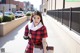 A woman in a red and black plaid dress is walking down the street.