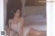 A woman in a white lingerie sitting on a bed.